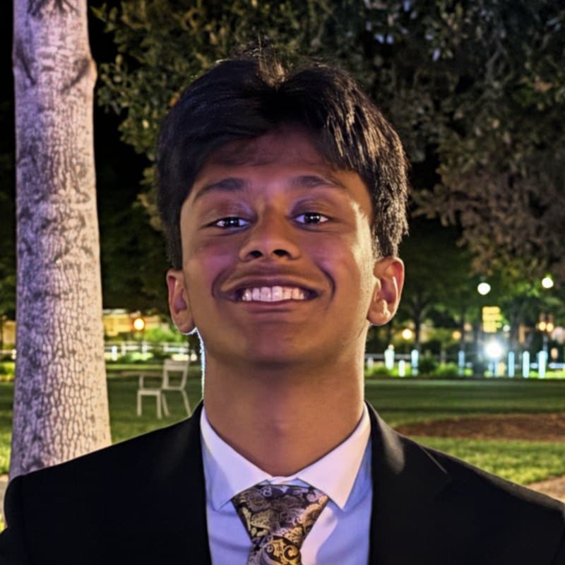 Avyaya Kumar, smiling, in a suit and patterned tie, outside at night